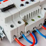 Nowoczesna przepięciówka z czerwonymi i niebieskimi przewodami, gotowa chronić instalację elektryczną.