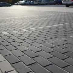 Szary parking wyłożony kostką brukową holland. W tle widać zaparkowane samochody.