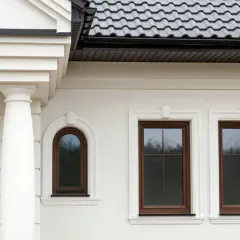 Elegancki gzyms zdobi białą elewację domu, podkreślając klasyczny styl.
