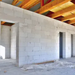 Wnętrze domu w budowie, ściany z bloczków suporeks, widoczne drewniane krokwie dachu.