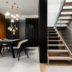 Nowoczesna jadalnia z drewnianymi schodami i szklaną balustradą.