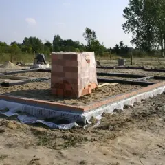 Rozpoczęcie budowy domu: wykopy pod fundamenty, ułożone bloczki i paleta cegieł.