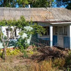 Stary, niebieski dom z falistym dachem, otoczony zielenią. To typowe **grunty rolne zabudowane**, gdzie życie toczy się w zgodzie z naturą.