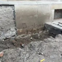 Prace przy podbijaniu fundamentów. Widoczny wykop i fragmenty muru.