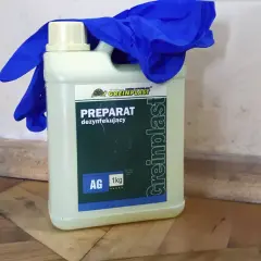 Preparat na grzyba na ścianie, wraz z niebieskimi rękawicami ochronnymi, gotowy do walki z pleśnią w rogu pomieszczenia.