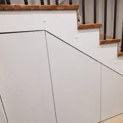 Nowoczesna wnęka pod schodami z białymi frontami, idealna na przechowywanie. Pomysły na zagospodarowanie przestrzeni.