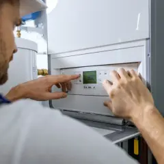 Technik reguluje piec gazowy, sprawdzając koszt instalacji gazowej.
