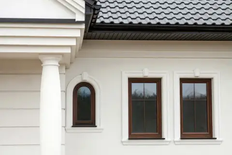 Elegancki gzyms zdobi białą elewację domu, podkreślając klasyczny styl.