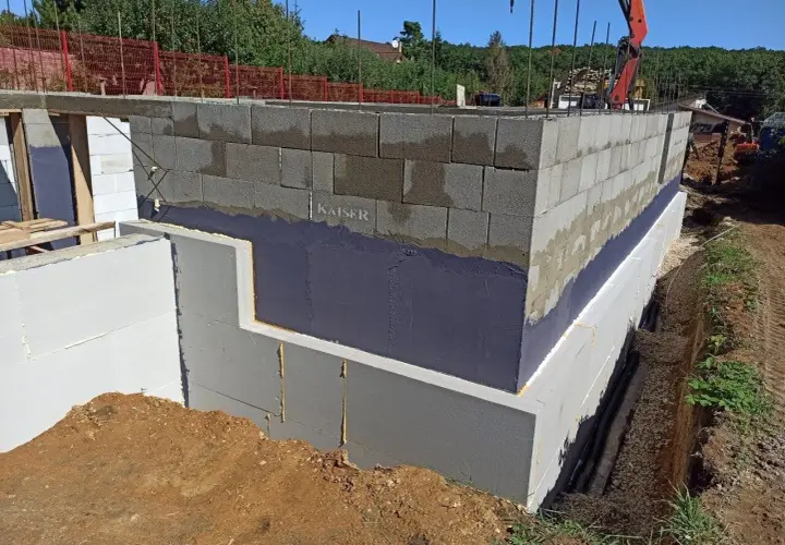 Fundament budynku z bloków betonowych zabezpieczony hydroizolacją. Widoczna izolacja termiczna i przeciwwilgociowa.