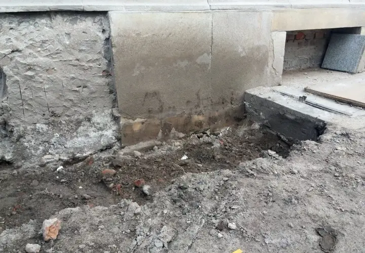 Prace przy podbijaniu fundamentów. Widoczny wykop i fragmenty muru.