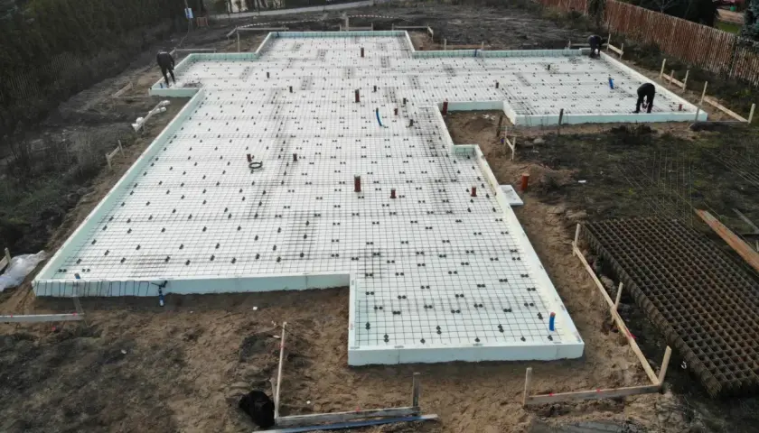 Budowa domu w toku. Widać zbrojenie i styropian na płycie fundamentowej, przygotowywanej pod fundament punktowy.