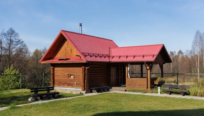 Drewniany domek z czerwoną dachem, idealny na wynajem. Możliwa dotacja na taki domek.