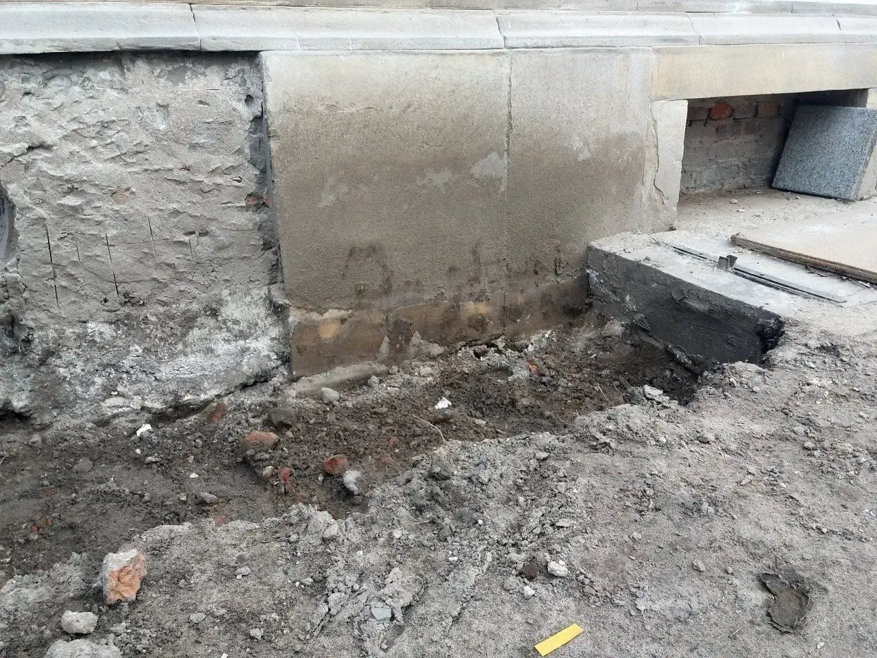 Prace przy podbijaniu fundamentów. Widoczny wykop i fragmenty muru.